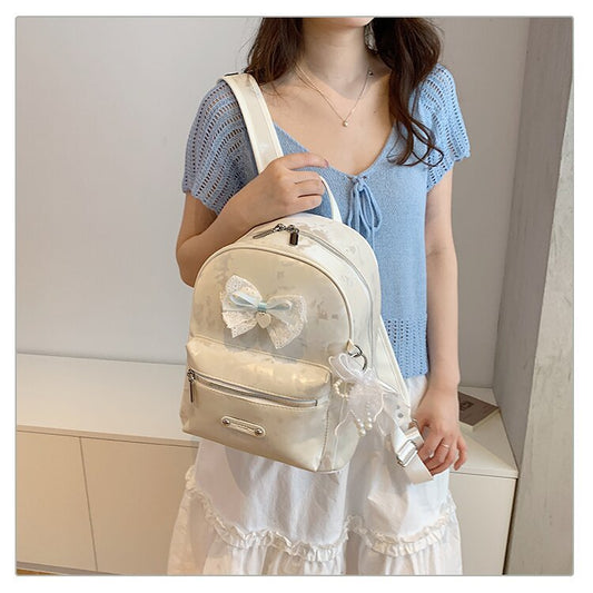 White bow-accent backpack worn with a blue and white casual outfit