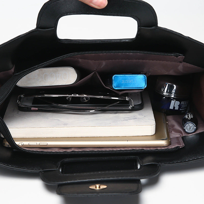 Open black cutout-handle crocodile-embossed bag showing divided interior